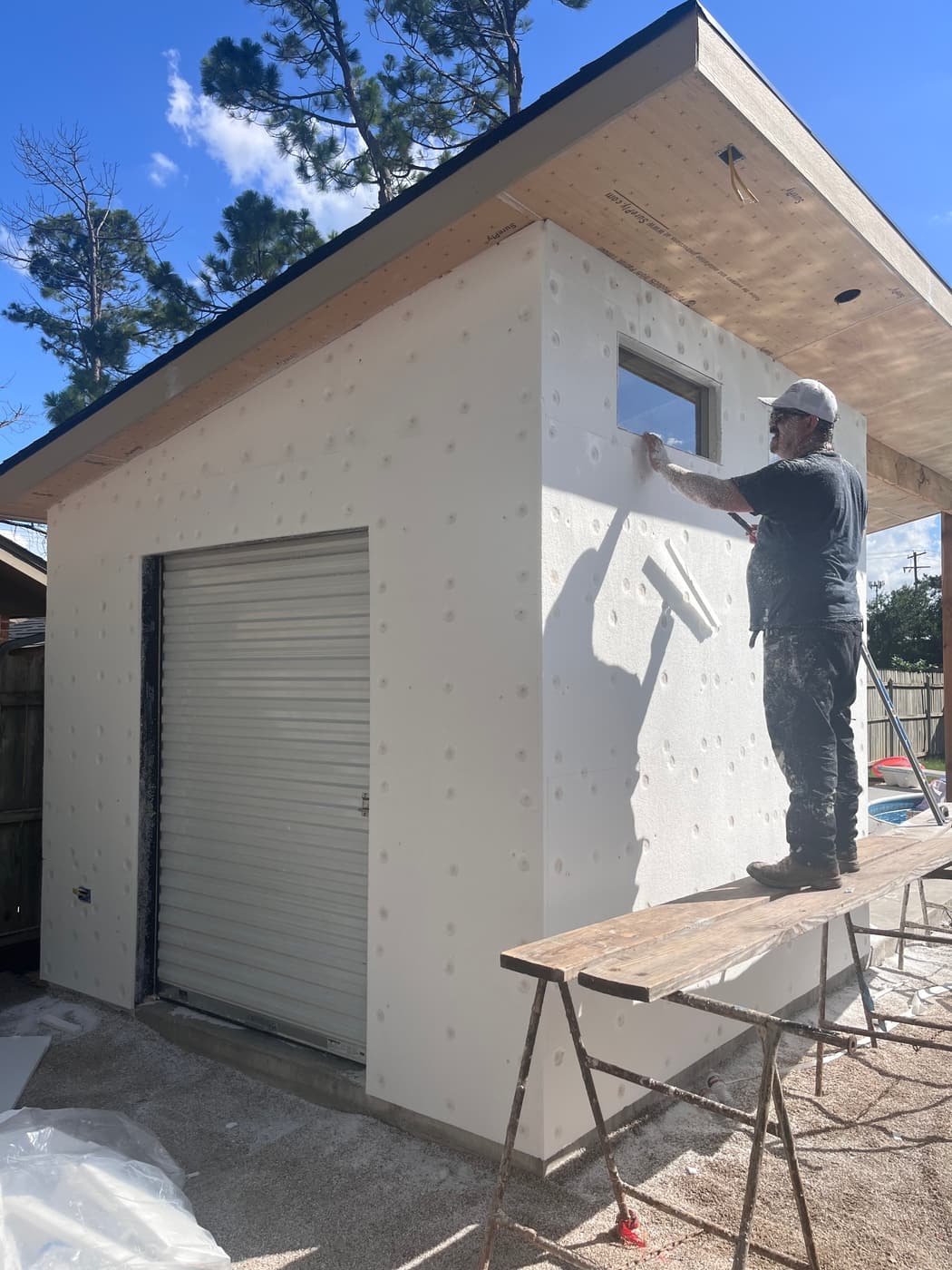 Before: applying base coat over EIFS foam insulation board on a backyard studio