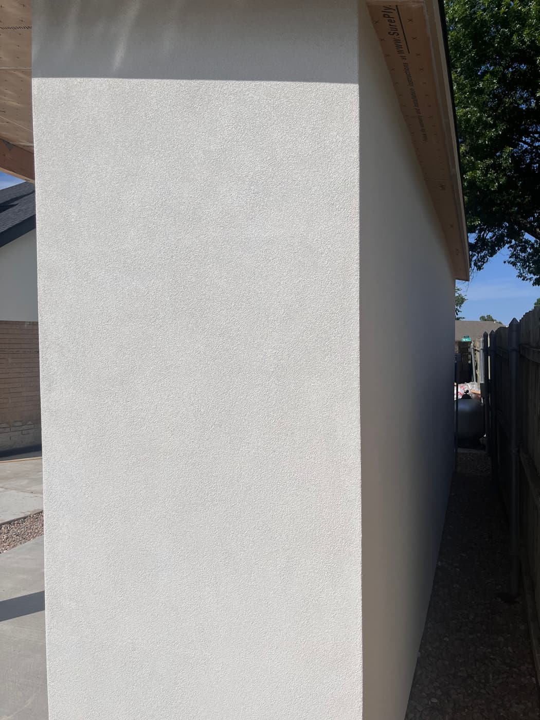 Freshly finished textured stucco wall along a home side yard